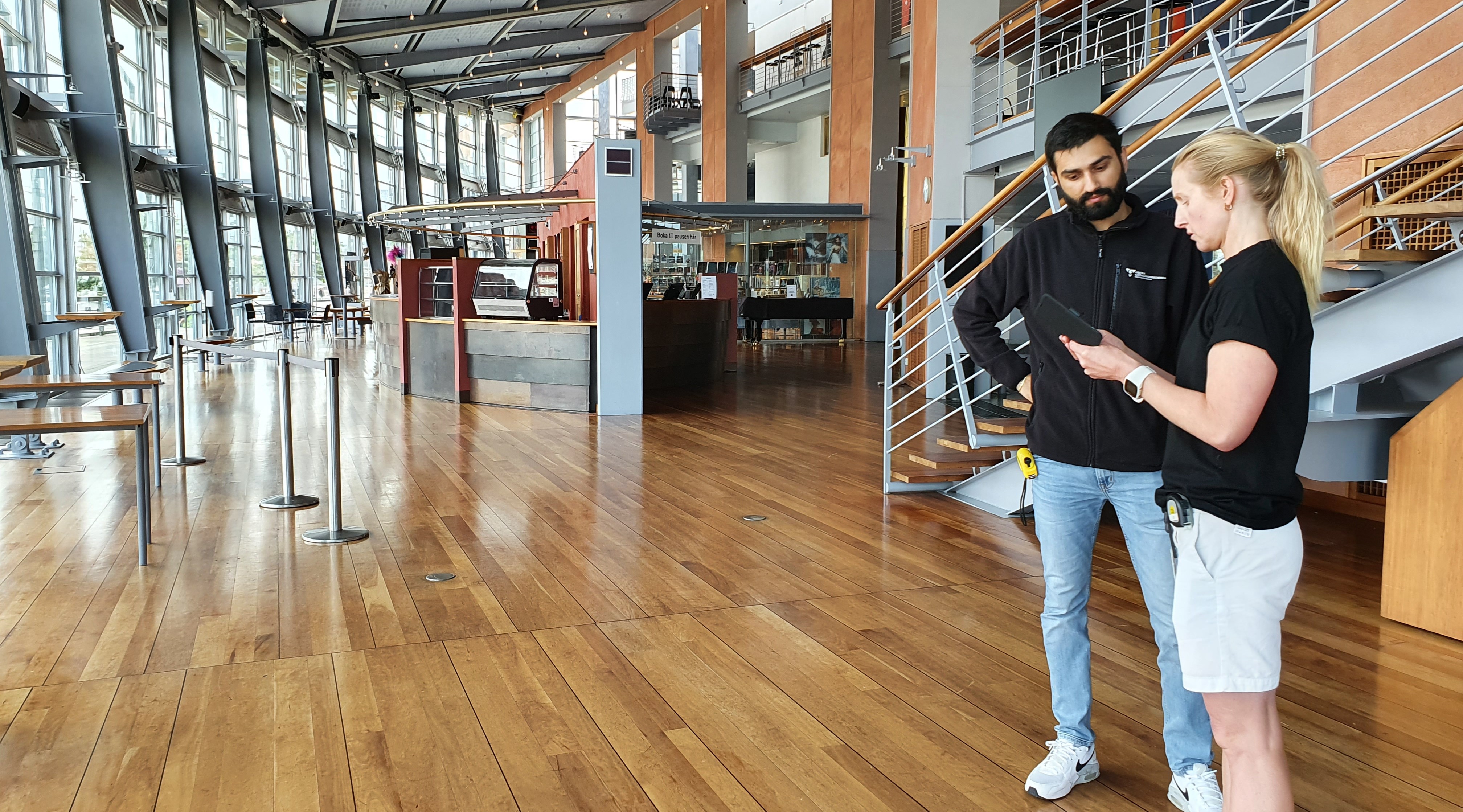 Två personer står och inventerar i en iPad i entréutrymmet på Göteborgsoperan.